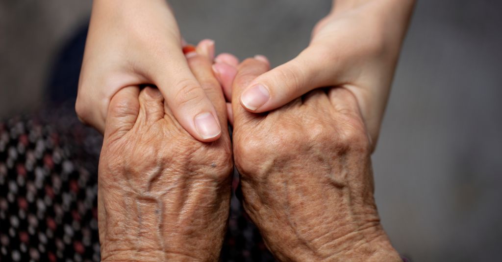 Cosa fare se l’anziano rifiuta la badante: nella foto un caregiver tiene le mani a un anziano