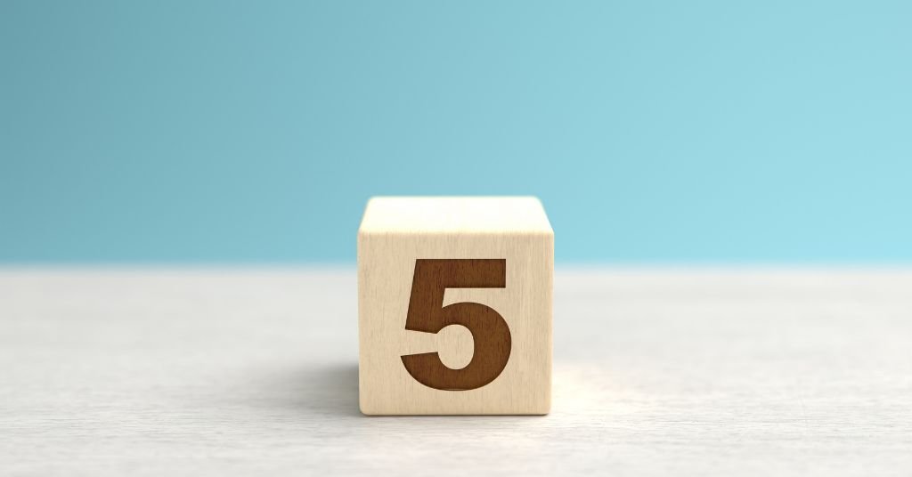 In foto un cubo di legno con impresso il numero 5.