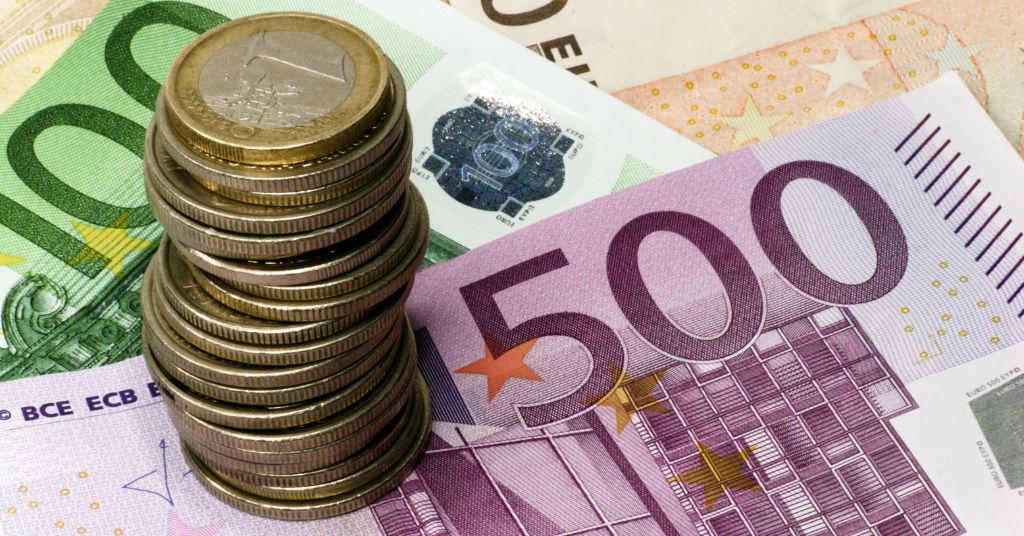 Torre di monete in euro su banconota da 500 euro e alle spalle una banconota da 100 euro