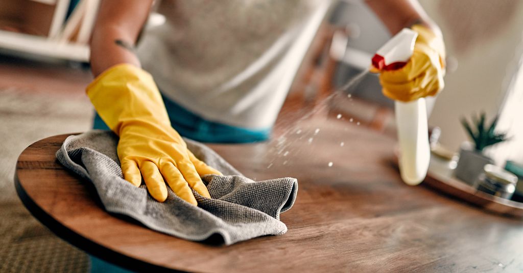 Pulire casa durante i permessi con Legge 104? Nella foto: una donna sta pulendo casa.