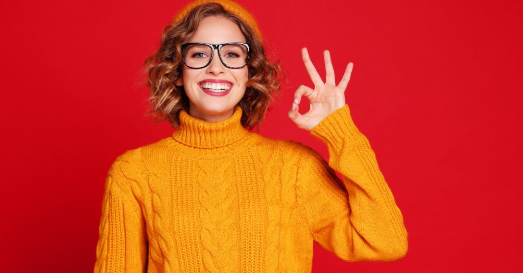 Congedo con Legge 104 a un familiare e permessi a un altro; si può. Nella foto: una donna fa il segno di "OK" con le dita.